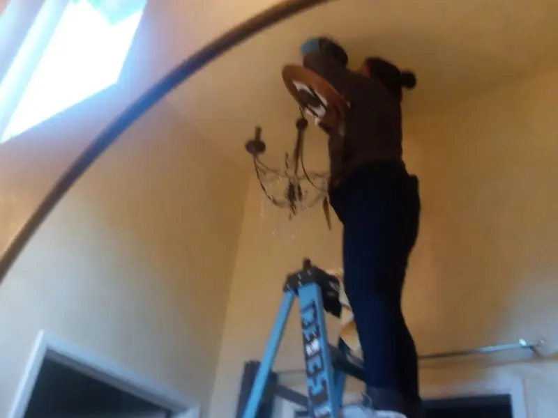 Electrician installing a chandelier in a Linda residence